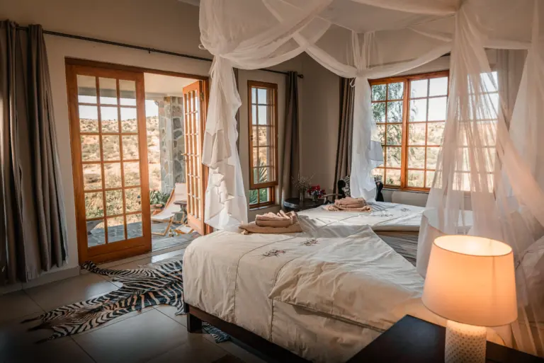 Komfort mit Aussicht – gemütliches Farmzimmer mit großen Fensterfronten und privater Terrasse.